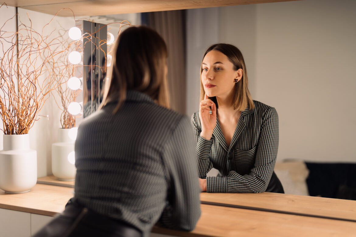 Lovely woman looking at her reflection in the mirror