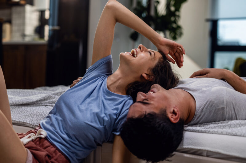 Young cheerful couple laughing together in the bedroom.